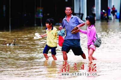 樂昌市政府前和街道被水浸,一位家長帶著孩子涉水而行。　　谷立輝童銅韶朱裕超攝