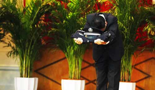 原市局刑警總隊(duì)二支隊(duì)副支隊(duì)長(zhǎng)鄭某手托警服警帽向全場(chǎng)鞠躬。圖片來(lái)源：重慶晚報(bào)
