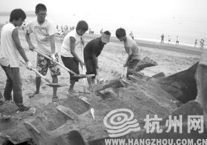 大連市金石灘國賓浴場，工作人員將帶有油污的沙子清理掉。