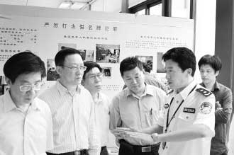圖為公安部經(jīng)偵局副局長(zhǎng)高峰(右)向公安部特邀監(jiān)督員們介紹“亮劍”行動(dòng)展覽情況。 