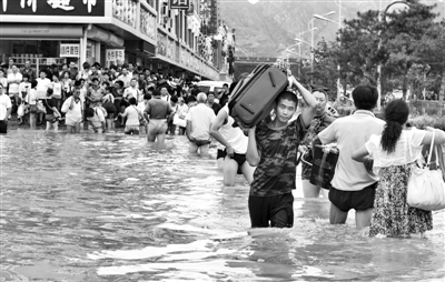 昨日，一名消防戰(zhàn)士在秦皇島市山海關(guān)火車站站前廣場涉水幫助旅客運送行李。 新華社發(fā)