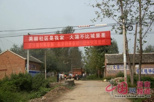 死者的家屬在村口迎接前來(lái)吊唁的親友，紅色的橫幅看上去更具諷刺意味。