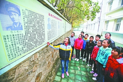 上圖：學(xué)校文化墻前，小講解員講述開國(guó)將軍杜義德的故事。記者何曉剛 攝