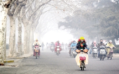 昨天上午，中原路，行人在霧霾中騎車出行，很多行人戴上了口罩。