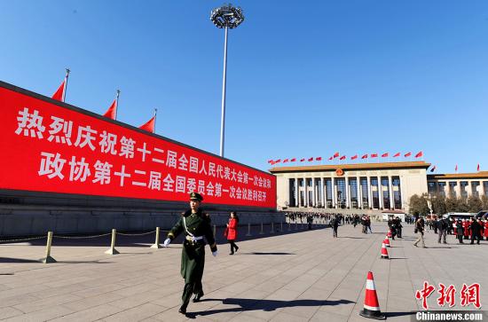 3月4日，北京晴空萬里，武警從北京天安門廣場大型顯示屏前走過。3月5日上午，十二屆全國人大一次會(huì)議將隆重開幕。中新社發(fā) 劉忠俊 攝