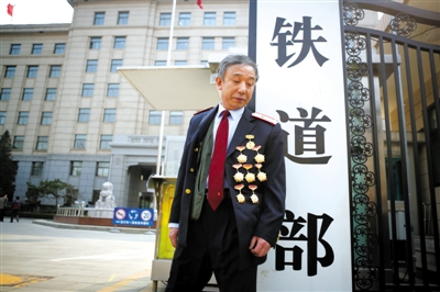 3月14日，鐵道部大門口，一位胸前掛著多枚勛章的鐵道部老職工與鐵道部牌子合影。 新京報記者 侯少卿 攝