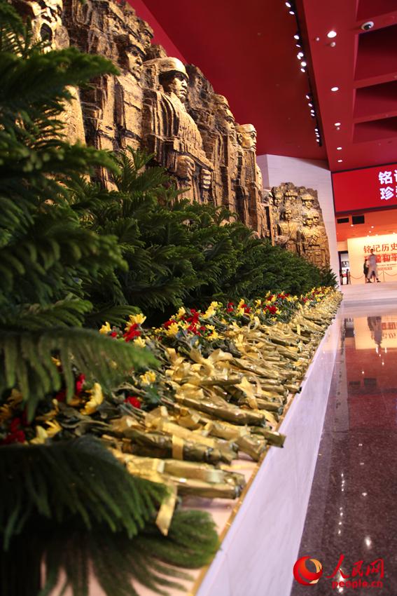 紀念館門廳的《銅墻鐵壁》雕塑墻，和人們獻上的花。邱越攝